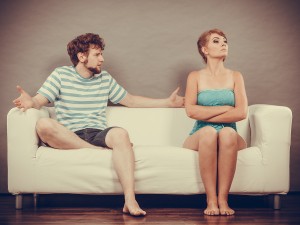 Man And Woman In Disagreement Sitting On Sofa
